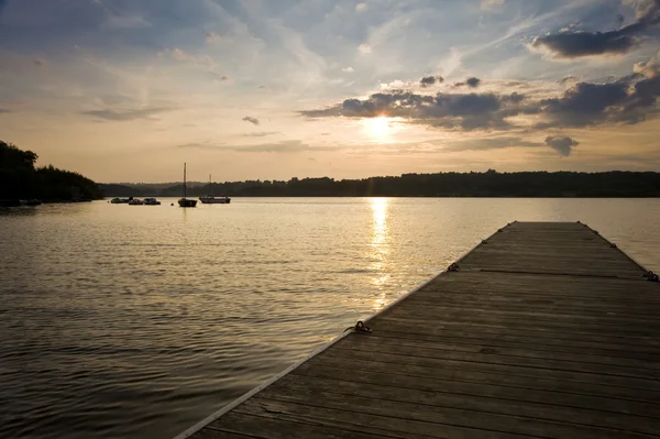 Longo cais molhe de madeira em lago calmo durante o pôr do sol de verão — Fotografia de Stock