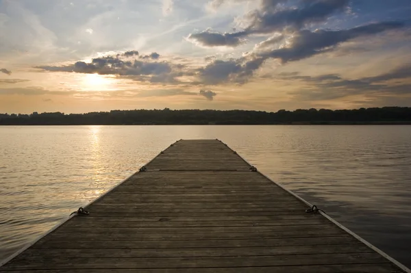 Bryggan långa träpiren i lugna sjön under sommaren solnedgången — Stockfoto