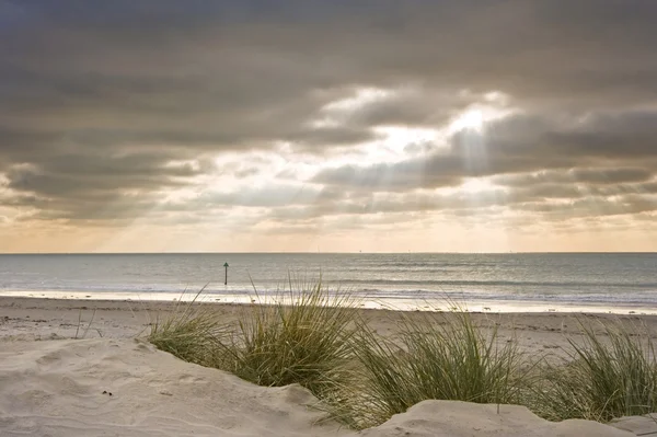 Stunning inspirational sunset image with glowing sun beams over grassy sand — Stock Photo, Image