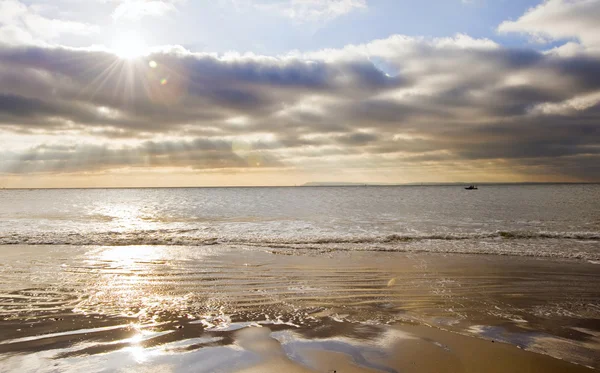 Потрясающее вдохновляющее изображение заката с яркими солнечными лучами над травянистым песком — стоковое фото