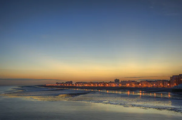 Mírové východ slunce nad hladké moře s městem ve vzdálenosti — Stock fotografie