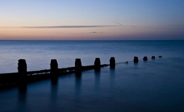 Ahşap groyne iskelesi ile pürüzsüz deniz üzerinde huzurlu gündoğumu — Stok fotoğraf