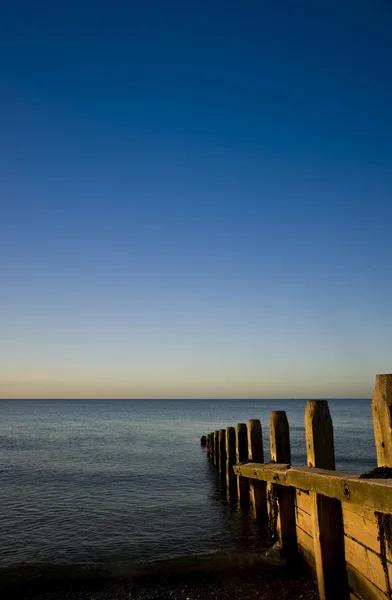 Tranquillo alba sul mare liscio con pontile groyne in legno — Foto Stock