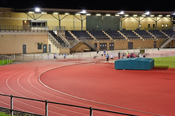 stock image Athletes night training in floodlight stadium