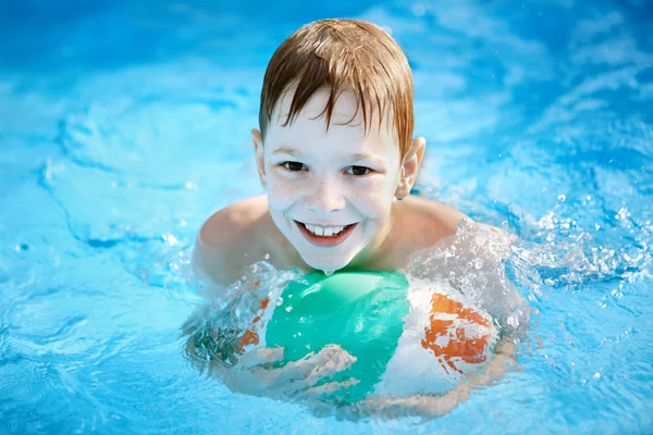 Мальчик с мячом в бассейне — стоковое фото
