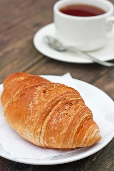 Fresh-baked croissant and cup of tea — Stock Photo, Image