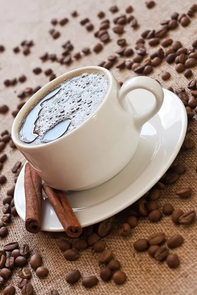Чашка кави та кавових зерен на мішкуватому матеріалі — стокове фото