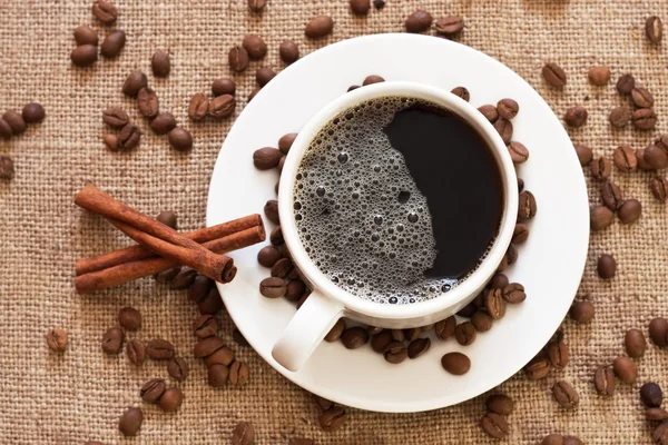 Чашка кави та кавових зерен на мішкуватому матеріалі — стокове фото