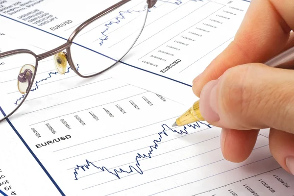 Hand met pen op een financieel verslag — Stockfoto