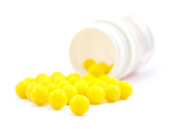 Gult piller från flaska på vita — Stockfoto