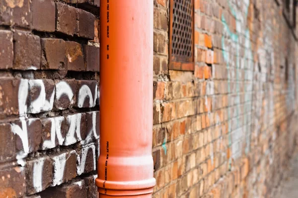 Sewage pipe on brick abandoned wall — Stock Photo, Image