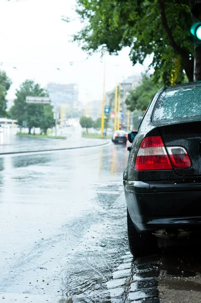 Close-up tiro de um carro de estacionamento na chuva com fundo embaçado — Fotografia de Stock