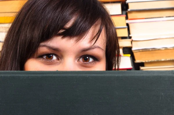 Ragazza si nasconde dietro il libro con sfondo sfocato — Foto Stock