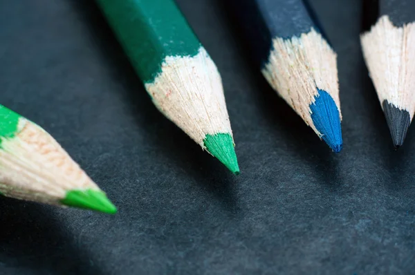 Färgglada pennor på mörk bakgrund uppradade — Stockfoto