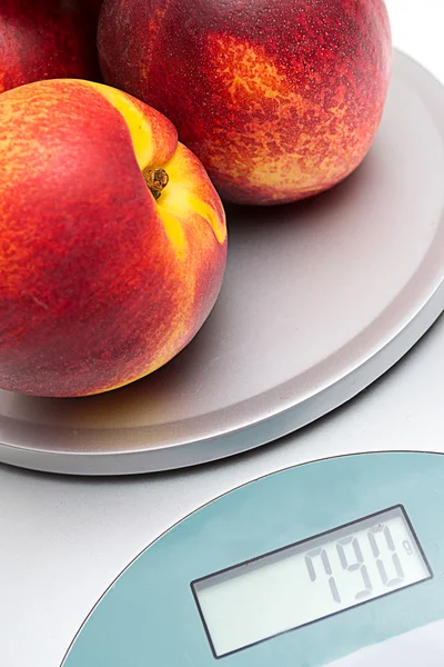 stock image Peaches on the scales on a white background