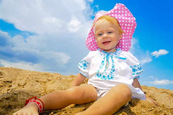 Niño sonriente sentado en una playa —  Fotos de Stock