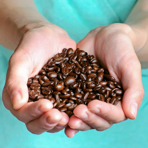 Koffiebonen op de handen — Stockfoto