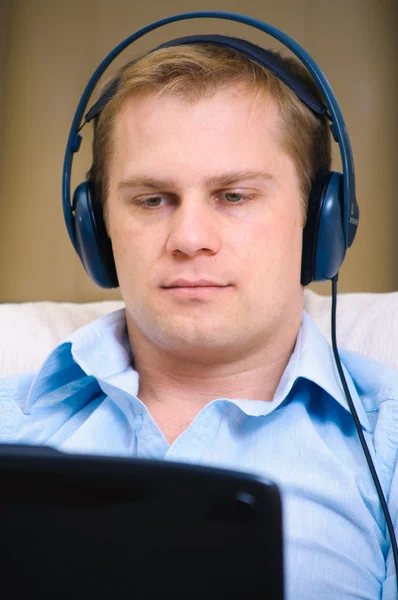Przypadkowy mężczyzna słuchania muzyki w słuchawkach w domu — Zdjęcie stockowe