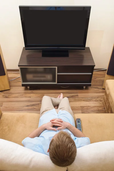 Uomo sdraiato sul divano a guardare la TV a casa . — Foto Stock