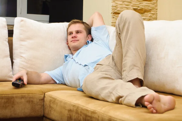 Homem deitado no sofá assistindo TV em casa . — Fotografia de Stock