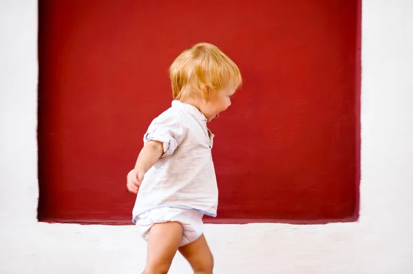 Feliz bebê bonito correndo contra a parede — Fotografia de Stock