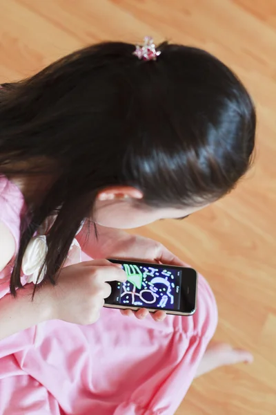 Маленькая девочка рисует на современном сенсорном экране телефона — стоковое фото
