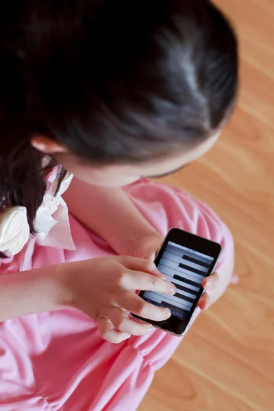 Dziewczynka gry na fortepianie na telefon z ekranem dotykowym nowoczesne — Zdjęcie stockowe