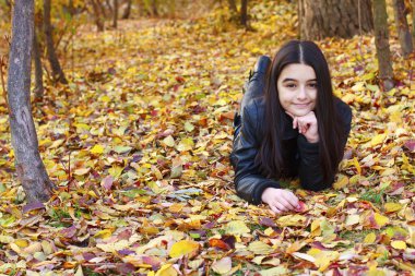 Teenager laying on leaves clipart