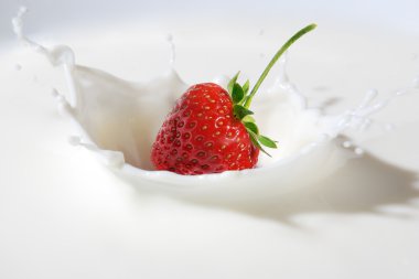 Delicious strawberry splashing into milk clipart