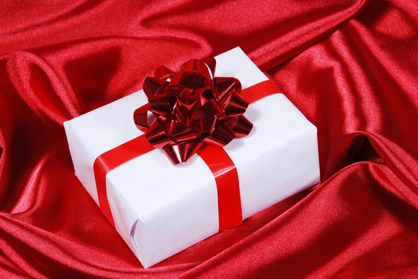 Подарункова коробка на фоні червоного атласу — стокове фото