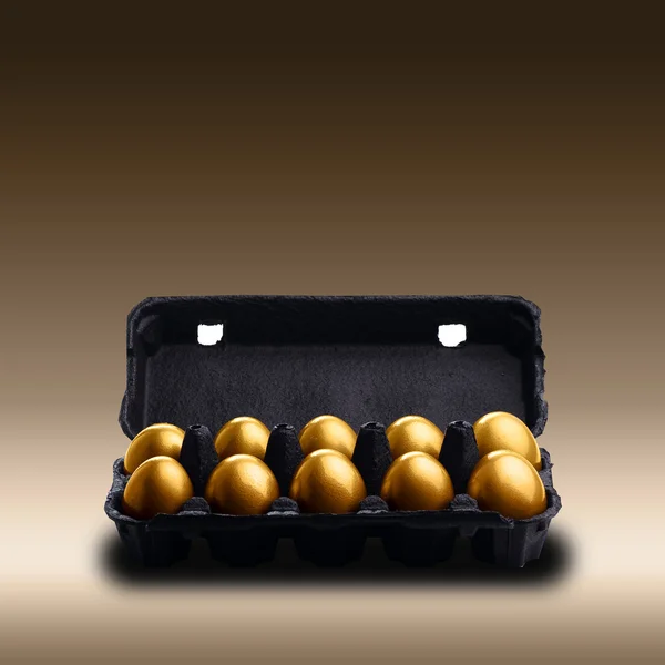 Gold eggs in a black carton — Stock Photo, Image