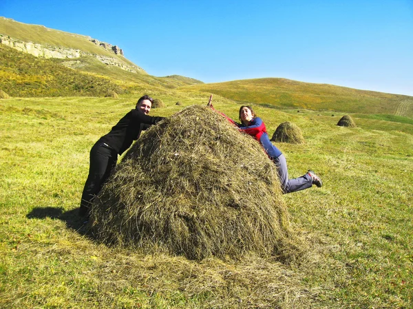 Dvě vtipné dívky a zásobníku sušené trávy — Stock fotografie