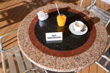 Fresh orange juice and cappuccino on no smoking table clipart