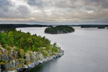 Small stone islands in swedish fiord at sunset clipart