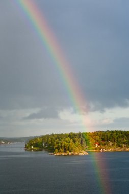 Rainbow in rain during sunshine in Baltic sea clipart