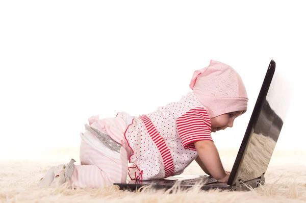 Младенец и ноутбук на ковре — стоковое фото