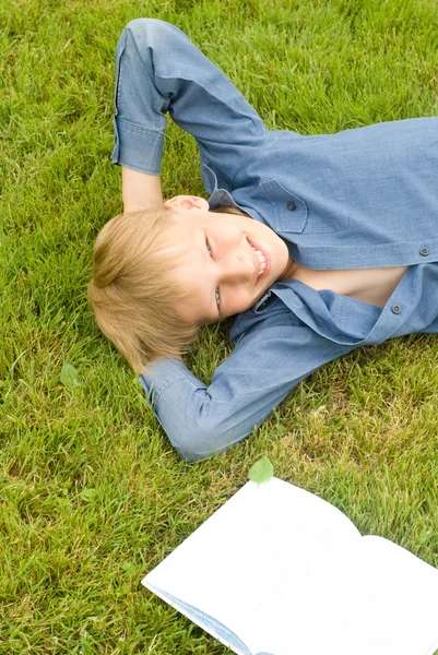 Junge mit Buch auf Gras — Stockfoto