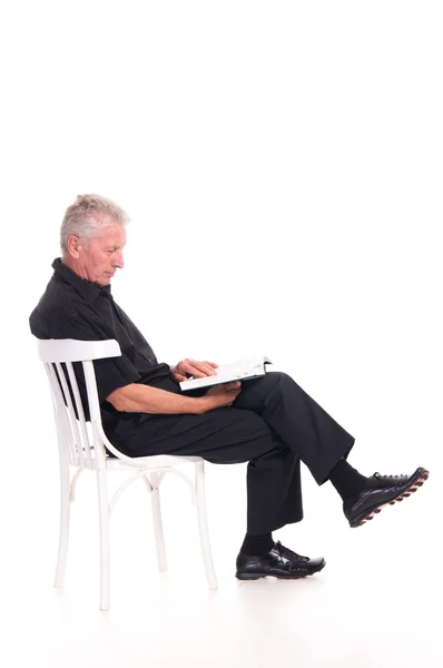 Yaşlı adam koltuğa okuma — Stok fotoğraf