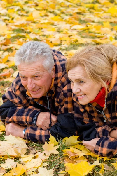 Old couple lying on leaves — Stock Photo, Image