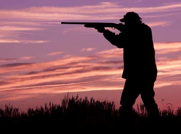 Jägare skjuta hagelgevär i solnedgången — Stockfoto