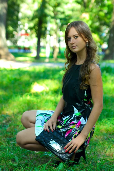 Mooi meisje in het park op een gras — Stockfoto