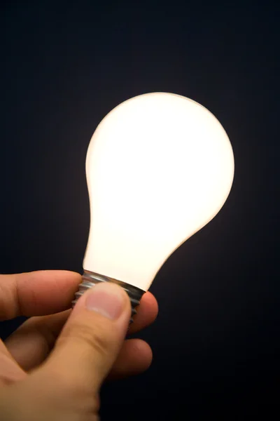 Mão segurando uma lâmpada brilhante — Fotografia de Stock