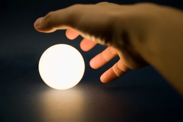 Mão tocando uma bola brilhante — Fotografia de Stock