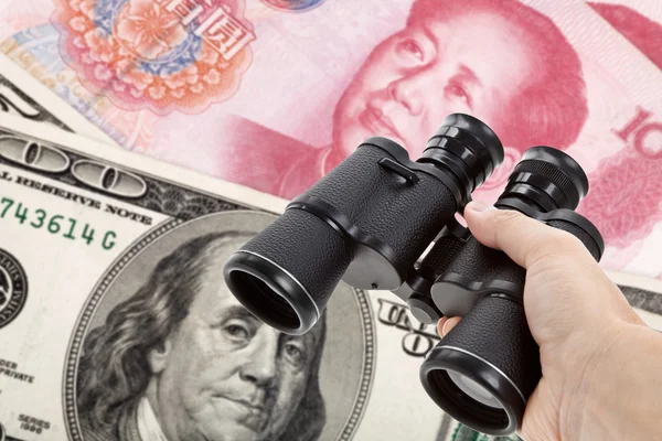 Бинокли и доллар, китайский юань — стоковое фото