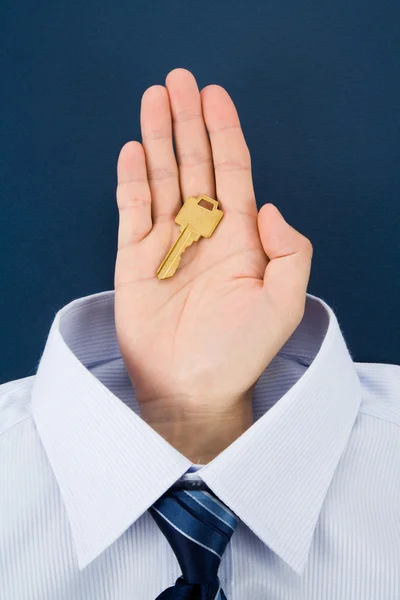 Mão segurando uma chave dourada — Fotografia de Stock