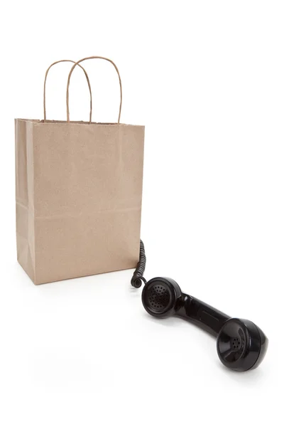 Brown paper shopping bag and telephone — Stock Photo, Image