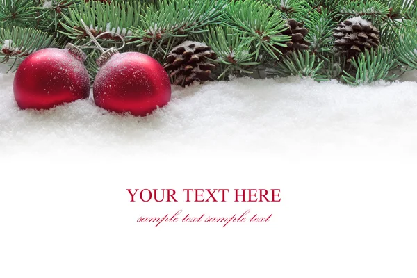 Červené vánoční koule a větev stromu jedle na bílém sněhu. — Stock fotografie