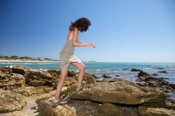 Mujer caminando sobre rocas al lado del océano — Foto de Stock