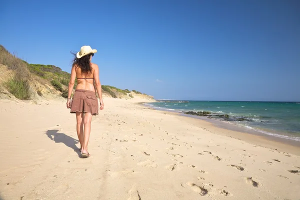 Kvinna med hatt walking stranden — Stockfoto