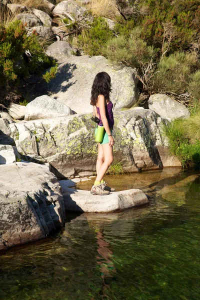 Боковая женщина на реке, наблюдающей за скалами — стоковое фото